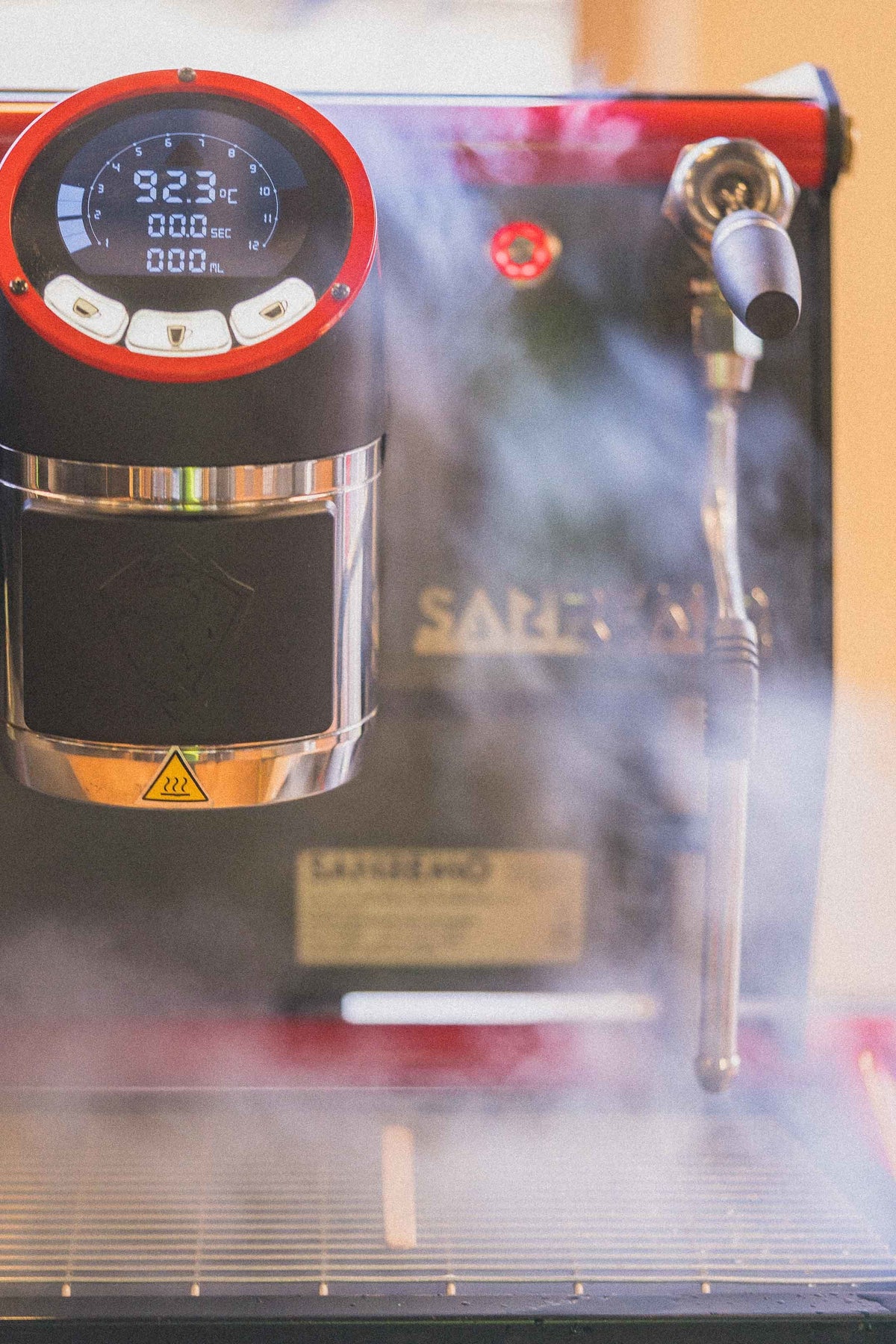 Steam rising from a polished espresso machine in a coffee station